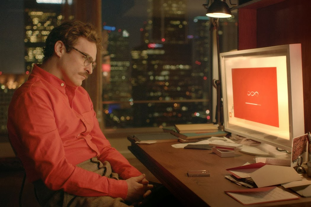 Theodore sitting at his desk beside Samantha's desktop operating system in Her