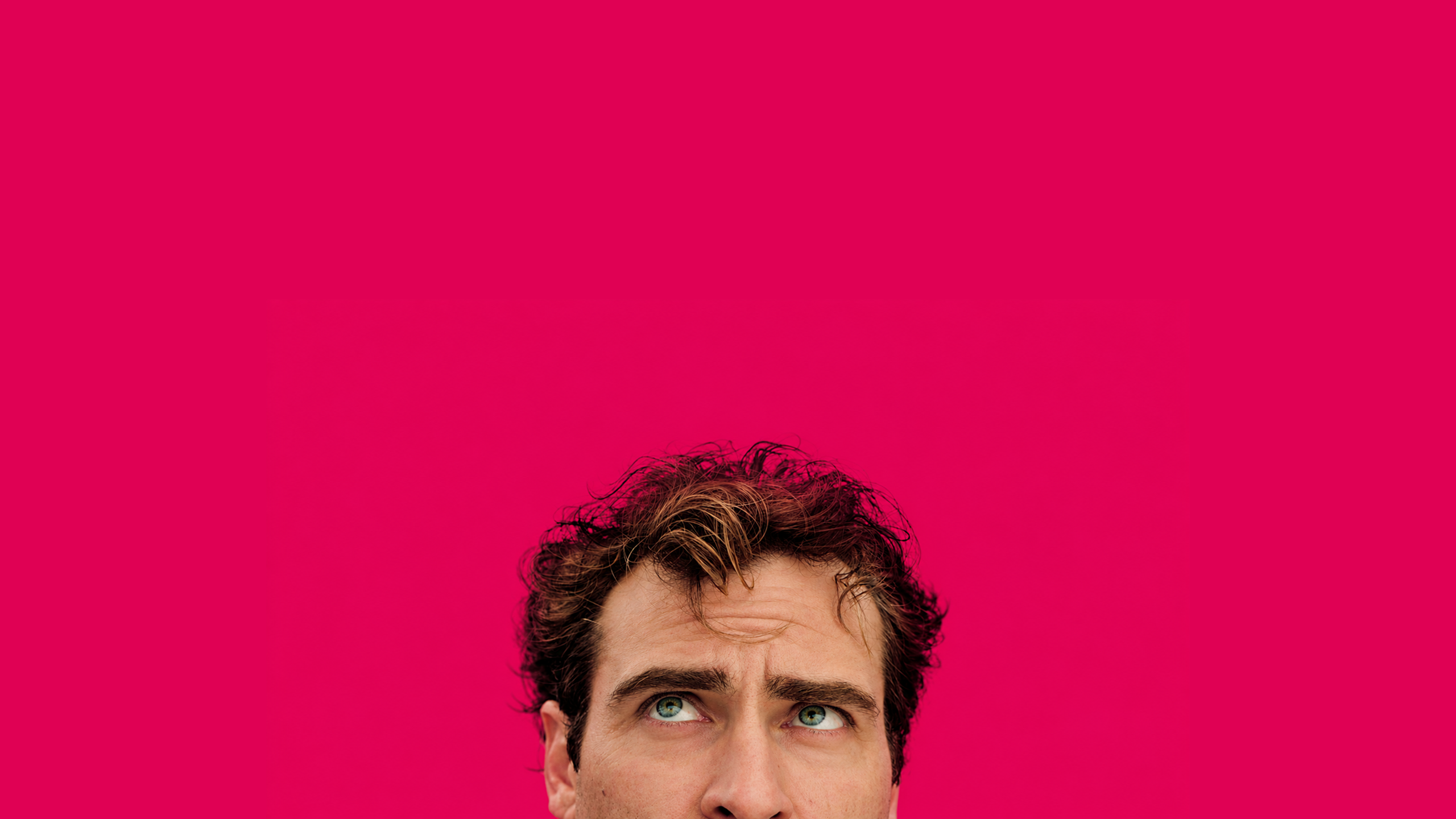 A man looking upward against a vivid pink background